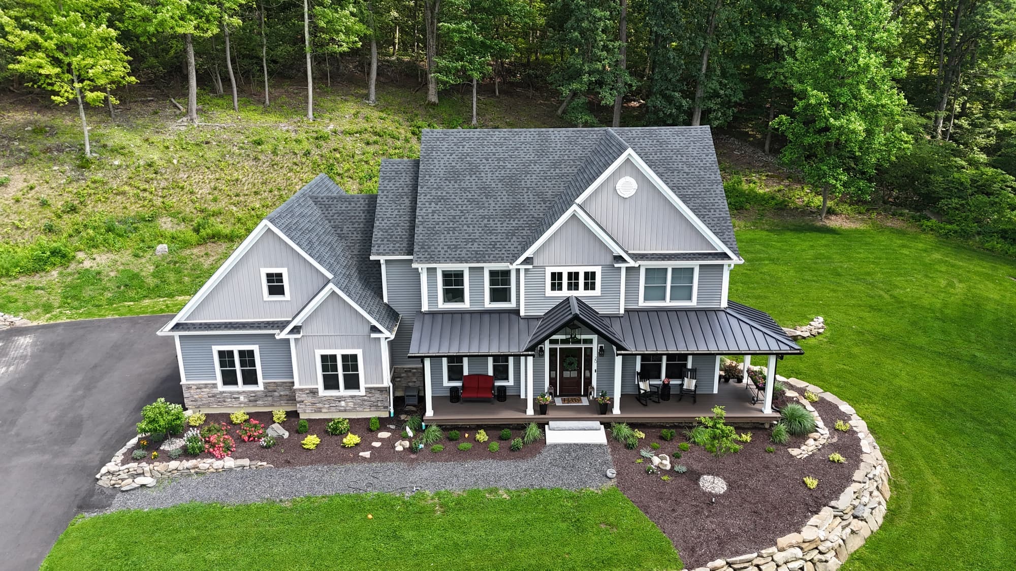 Drone view of a gray two story home with a new shingle roof and siding in Orange Lake, NY